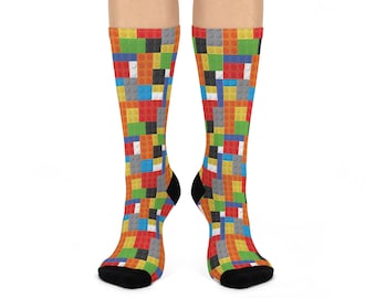 Könnte beinhalten: Kniestrümpfe mit einem bunten Muster aus Spielzeugbausteinen in Rot, Gelb, Grün, Blau und Schwarz. Die Socken haben schwarze Fersen und Zehen. Das Design ähnelt einem Mosaik.
