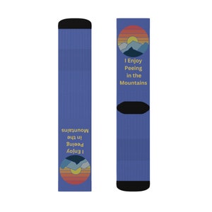 May include: A pair of blue socks with black heels and toes. Each sock features a circular graphic of a mountain range and setting sun, with the text "I Enjoy Peeing in the Mountains".