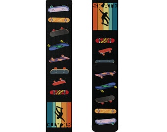 Op de afbeelding: Zwarte sokken met een skateboardthema. Eén sok heeft een skater-silhouet en het woord "SKATE" in een retro lettertype. De andere sok toont verschillende skateboardontwerpen. De sokken hebben een retro kleurenschema van oranje, blauwgroen en geel.