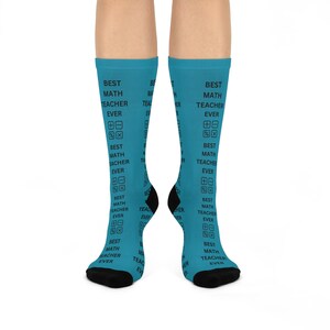 May include: A pair of turquoise socks with black heels and toes. The socks are printed with the words "BEST MATH TEACHER EVER" and math symbols. The socks are designed to be worn on the feet.