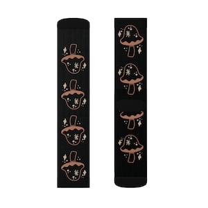 May include: Black socks featuring a repeating pattern of stylized brown mushrooms with white star and diamond accents. The socks have a black cuff and toe. These socks are a fun and whimsical accessory.