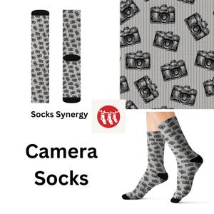 May include: Gray camera socks with a black heel and toe. The socks feature a repeating pattern of black camera illustrations. The words "Camera Socks" are printed in black. The brand name "Socks Synergy" is also visible.