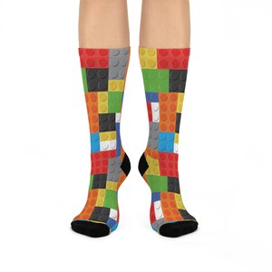 May include: A pair of colorful socks with a Lego brick pattern. The socks are black, red, yellow, blue, green, and gray.