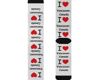 May include: A pair of white socks with a black cuff and red hearts. The socks have the text "I love Vancouver, Canada" repeated on them.