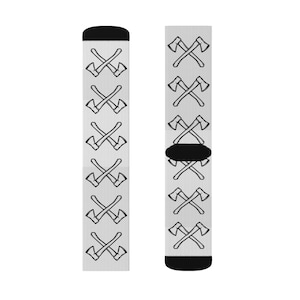 May include: A pair of crew socks with a light grey background and a repeating pattern of black crossed axes. The top and toe of each sock are black.