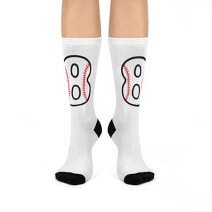 Könnte beinhalten: Weiße Socken mit einem schwarzen und roten Baseball-Motiv auf jeder Socke. Das Motiv ist ein Baseball mit der Nummer 8 darin.