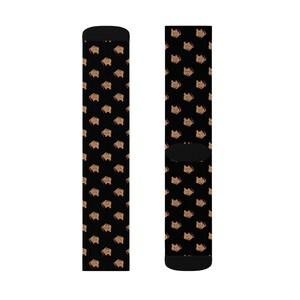 May include: A pair of black socks with a repeating pattern of cartoon bear faces in brown and pink. The socks have black heels and toes.