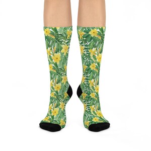 May include: A pair of socks with a floral pattern. The socks are green with yellow flowers and leaves. The socks are shown on a white background.