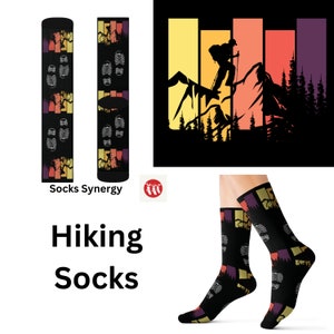 May include: Black hiking socks with a colorful mountain and sunset design. The socks feature a hiker graphic, footprints, and the words "Hiking Socks". The socks are shown on a person's legs.