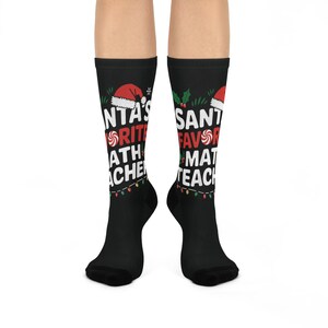 May include: Black socks with the text "SANTA'S FAVORITE MATH TEACHER" in white, red, and green. The socks feature Santa hats, candy canes, and Christmas lights. A festive gift for math teachers.