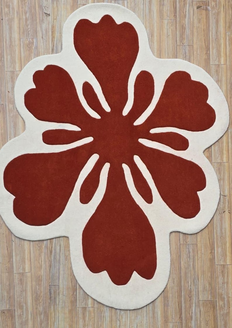 May include: A large, flower-shaped rug with a bold design. The rug features a vibrant red center with white petal outlines, creating a striking contrast. The rug's unique shape and color scheme make it a statement piece for any room.