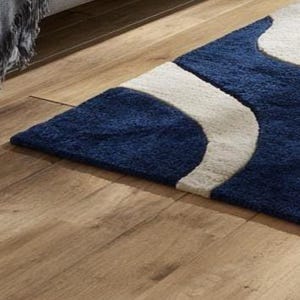 Modern blue and ivory wool rug with organic wave design, hand-tufted by Rugs By Mirzapur. This elegant carpet features soft texture and 3D carved details. Perfect for contemporary interiors, it brings a calming, ocean-inspired feel to living spaces with timeless handmade craftsmanship.