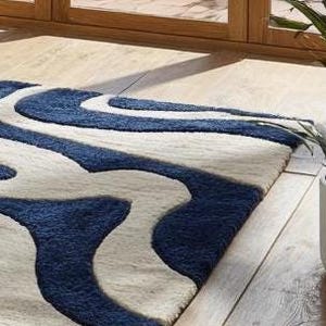 Elegant navy and ivory hand-tufted rug featuring smooth flowing lines and organic shapes. Made by Rugs By Mirzapur, this contemporary wool carpet adds sophistication to minimalist spaces. The plush, carved pile provides a soft texture and a modern statement for stylish homes.