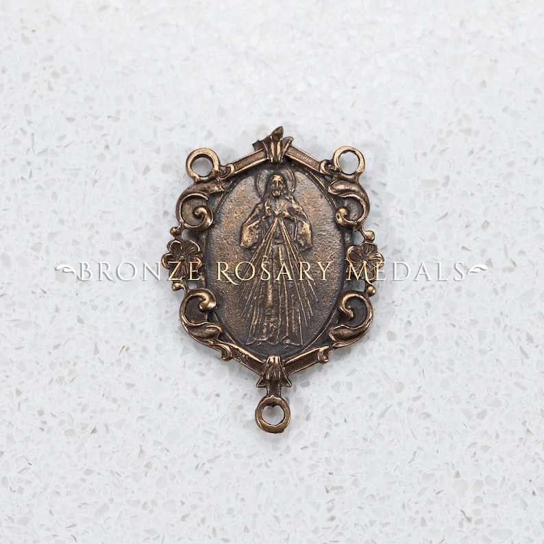 The Divine Mercy bronze center is surrounded by scrolls and flowers.  It is 1 3/8 inches tall a depicts Jesus displaying his Sacred heart.  This image is watermarked