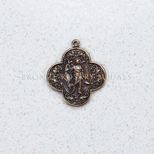 May include: Bronze-colored pendant with a four-leaf clover shape. The pendant features an image of a figure holding a sword and shield, surrounded by ornate detailing. The text "BRONZE ROSARY MEDALS" is visible.
