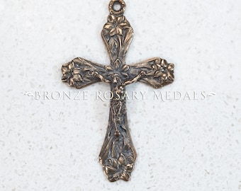 May include: Bronze crucifix pendant with floral detailing and the figure of Jesus Christ. The cross has a loop at the top for hanging and the text "BRONZE ROSARY MEDALS" is visible.