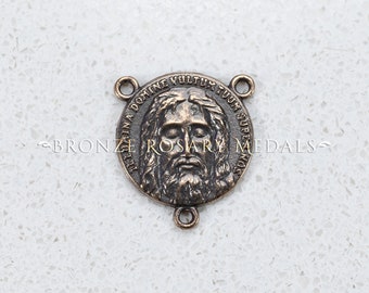 May include: A bronze-colored metal rosary center piece with a round face featuring a depiction of Jesus' face and the Latin phrase "Ecce Homo Domine Vultum Tuum Super Nos" around the edge.