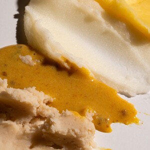 May include: Three different types of creamy, spreadable food products. The top layer is a light yellow color, the middle layer is a light orange color, and the bottom layer is a light beige color.