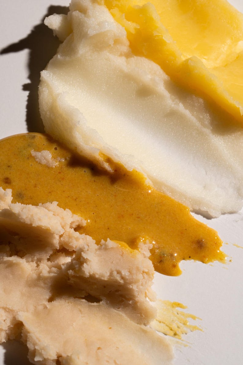 May include: Three different types of creamy, spreadable food products. The top layer is a light yellow color, the middle layer is a light orange color, and the bottom layer is a light beige color.