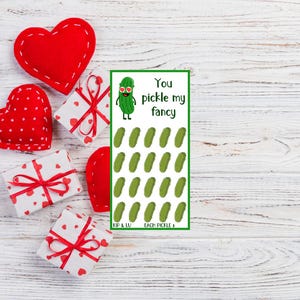 Op de afbeelding: Een Valentijnskaart met een groene augurk met een zonnebril en de tekst "You pickle my fancy". De kaart heeft een raster met 20 groene augurken.