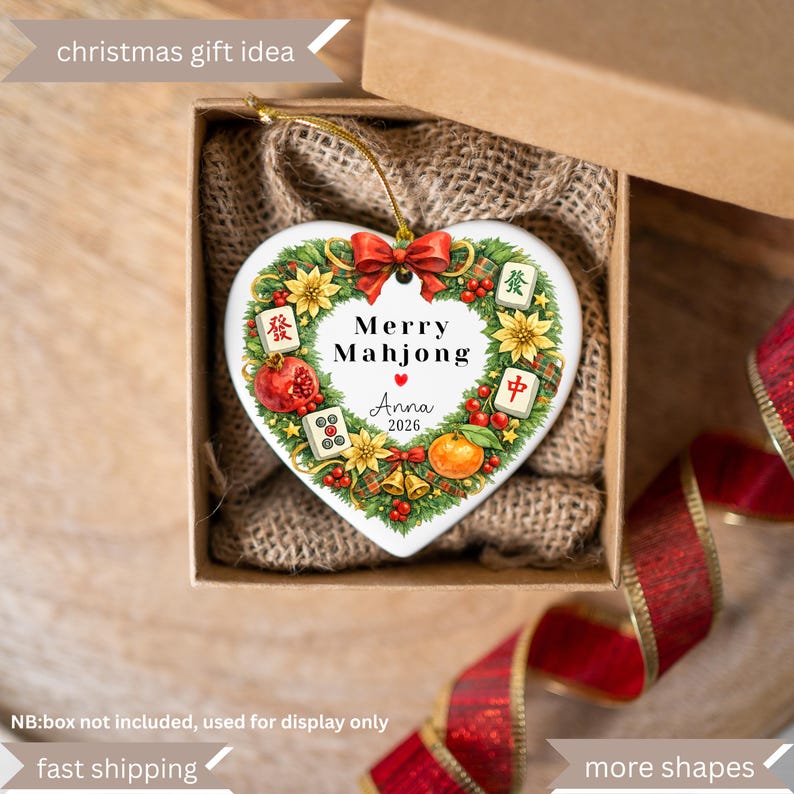 Pu&ograve; includere: Ornamento natalizio a forma di cuore con un design festivo. L'ornamento presenta il testo "Merry Mahjong" e "Anna 2026" circondato da una ghirlanda di fiori, frutta e tessere di Mahjong. &Egrave; presentato in una confezione regalo con fodera in juta.