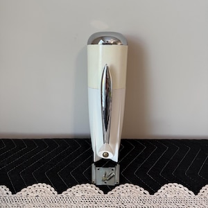 May include: A vintage cream and chrome electric can opener. The can opener has a chrome handle and a chrome top. The mounting bracket and screws are included. The can opener is approximately 10 inches tall.