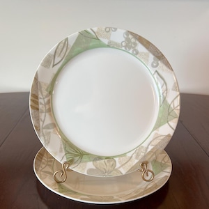 May include: Two ceramic dinner plates with a green and brown floral pattern. The plates are stacked on top of each other.