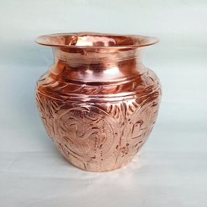 May include: A copper vase with intricate embossed designs. The vase has a rounded body and a wide mouth.