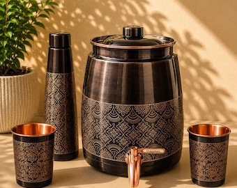 May include: A dark metallic water dispenser with a copper-toned spigot labelled Classinox, accompanied by a matching tall bottle and two tumblers. Each piece features a black finish with intricate, repeating copper-coloured geometric patterns.