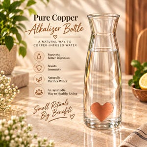 Puede incluir: Una botella de agua de vidrio transparente con un emblema de cobre en forma de corazón cerca de la base. El texto en la botella dice: Pure Copper Alkalizer Bottle, A NATURAL WAY TO COPPER-INFUSED WATER, Supports Better Digestion, Boosts Immunity, Naturally Purifies Water, An Ayurvedic Way to Healthy Living, Small Rituals Big Benefits.