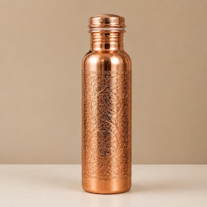 Pode incluir: Uma garrafa de água cilíndrica de cobre com acabamento metálico polido e um intrincado padrão floral gravado que cobre o corpo principal. A garrafa tem um gargalo estreito, um ombro arredondado e uma tampa de rosca a condizer com rebordo.