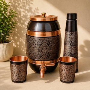 May include: A decorative copper and black water dispenser set. The set includes a barrel-shaped dispenser with a spigot, a tall water bottle, and two matching tumblers. All pieces feature an ornate floral pattern.