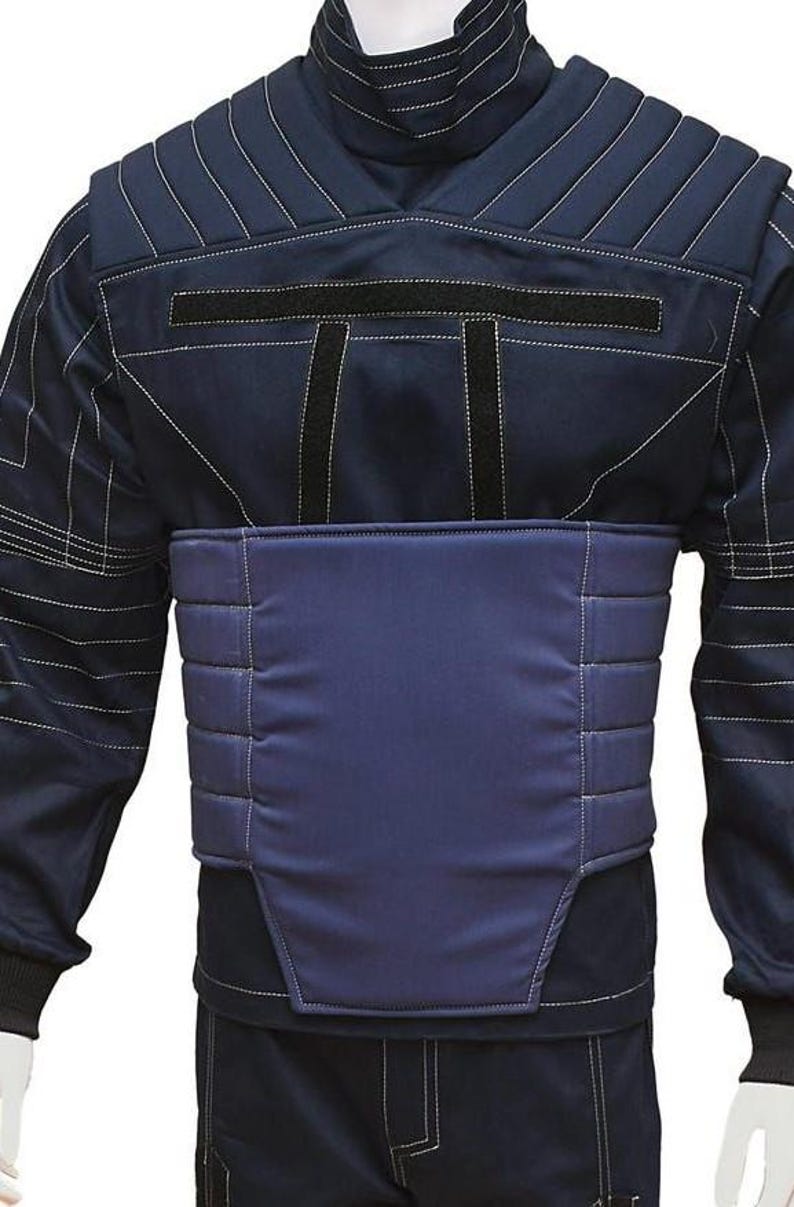 May include: Navy blue jacket with a high collar and white stitching details. The jacket features a padded chest panel and black accents. The design includes a structured silhouette, suitable for various activities.