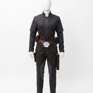 May include: A dark grey jumpsuit with a high collar, long sleeves, and a brown belt with pouches. The trousers have dark blue accents. The outfit is displayed on a mannequin.