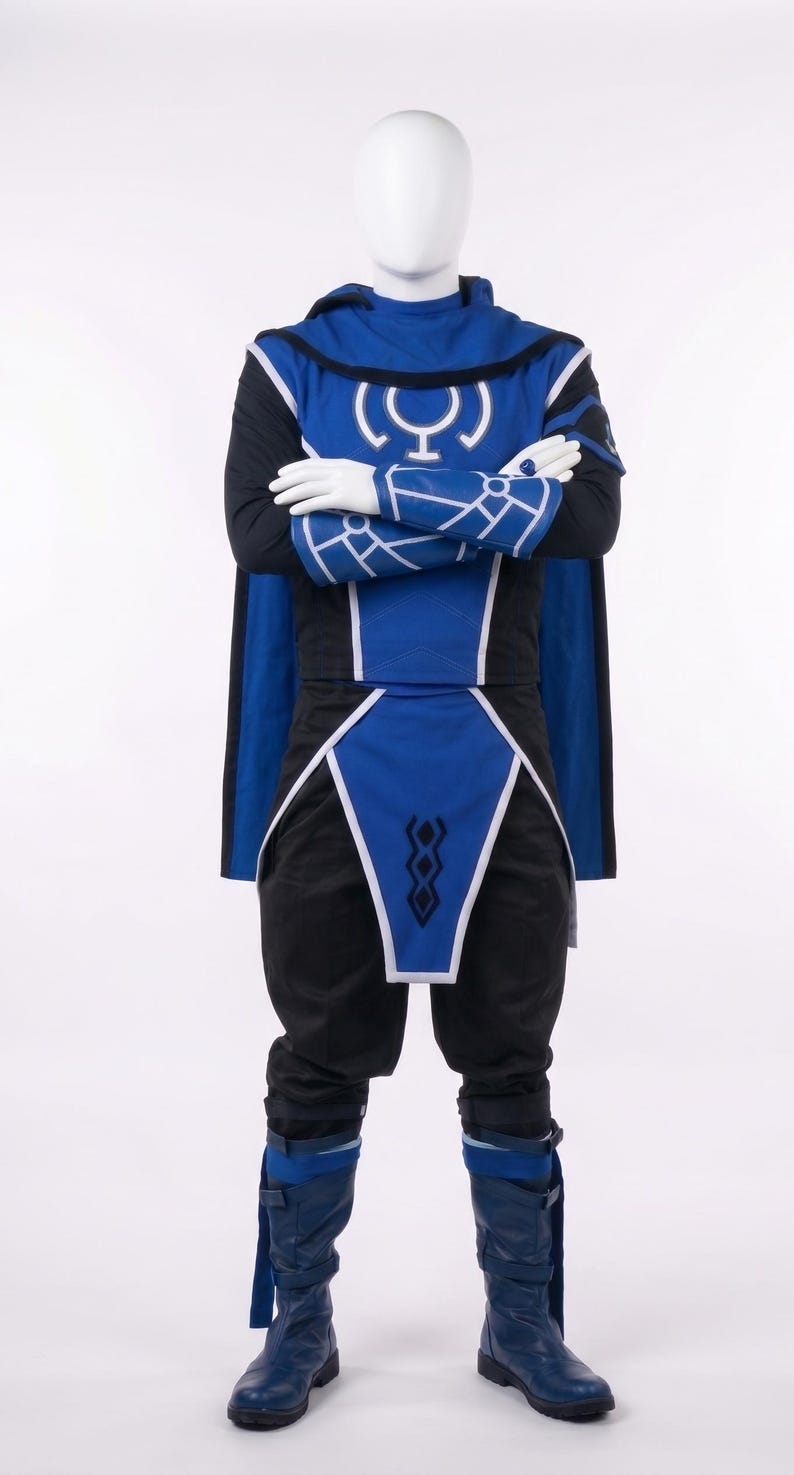 May include: A blue and black costume featuring a hooded tunic with a white circular symbol on the chest, matching arm gauntlets with white geometric patterns, a blue waist sash with a black diamond design, and blue boots with buckle straps.