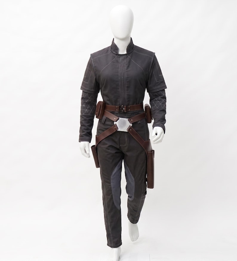 May include: A dark grey jumpsuit with a high collar, featuring a brown belt with pouches and a silver buckle. The sleeves have quilted detailing, and the trousers have grey accents. This costume is displayed on a mannequin.