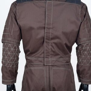 May include: A brown jacket with white stitching. The sleeves have geometric patterns, and the design is structured. The back view highlights the tailored fit and contrasting stitching details.