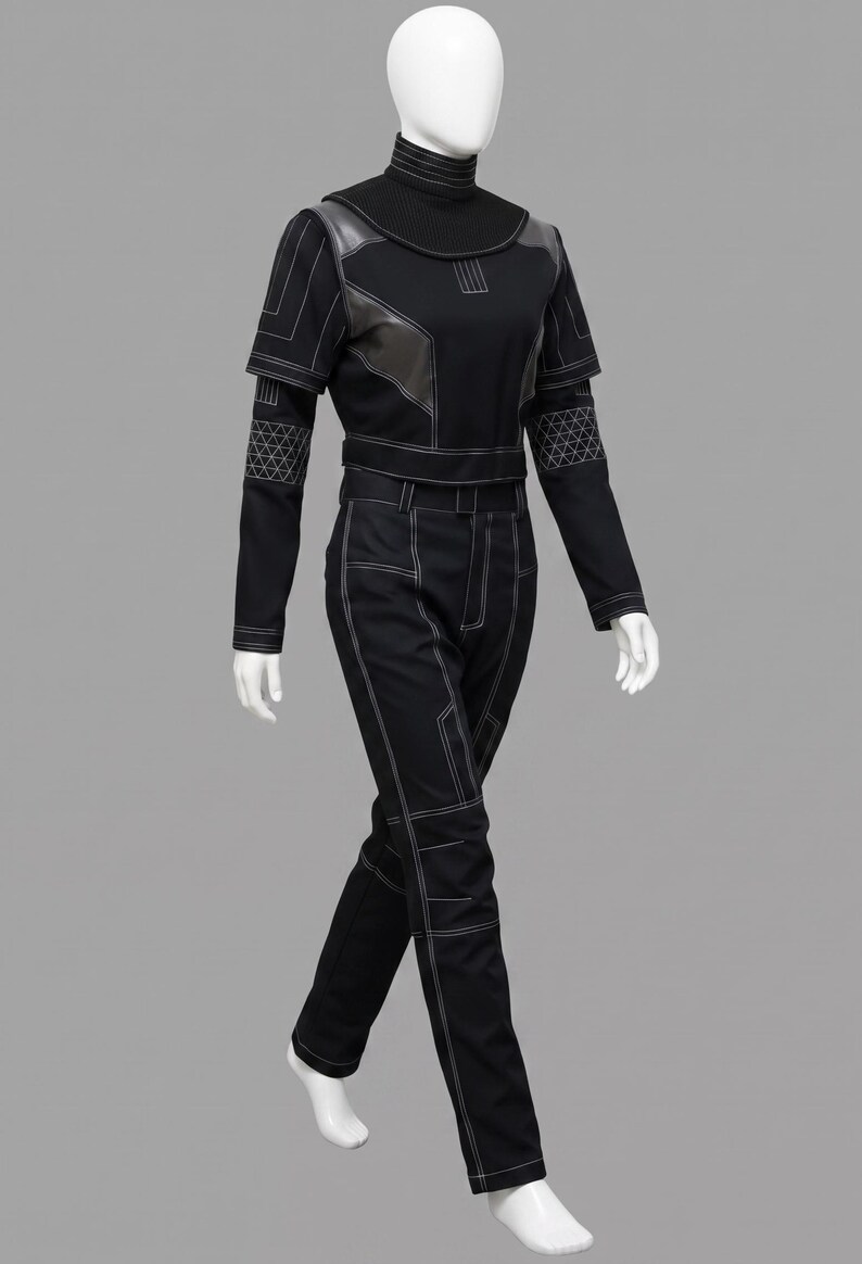 Peut inclure: Combinaison noire avec des coutures blanches. La tenue comprend un haut &agrave; col montant avec des d&eacute;tails en cuir et des manches longues. Le pantalon est droit. Le mannequin est sur fond gris.