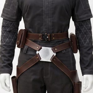 May include: A dark grey jumpsuit with white stitching and a brown leather belt and holster system. The outfit features a high collar, short sleeves, and a silver buckle. The trousers have grey panels on the sides.