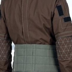 May include: A brown jumpsuit with geometric stitching on the shoulders and sleeves. The back view shows a light green quilted belt. Black velcro patches are visible on the upper arm.