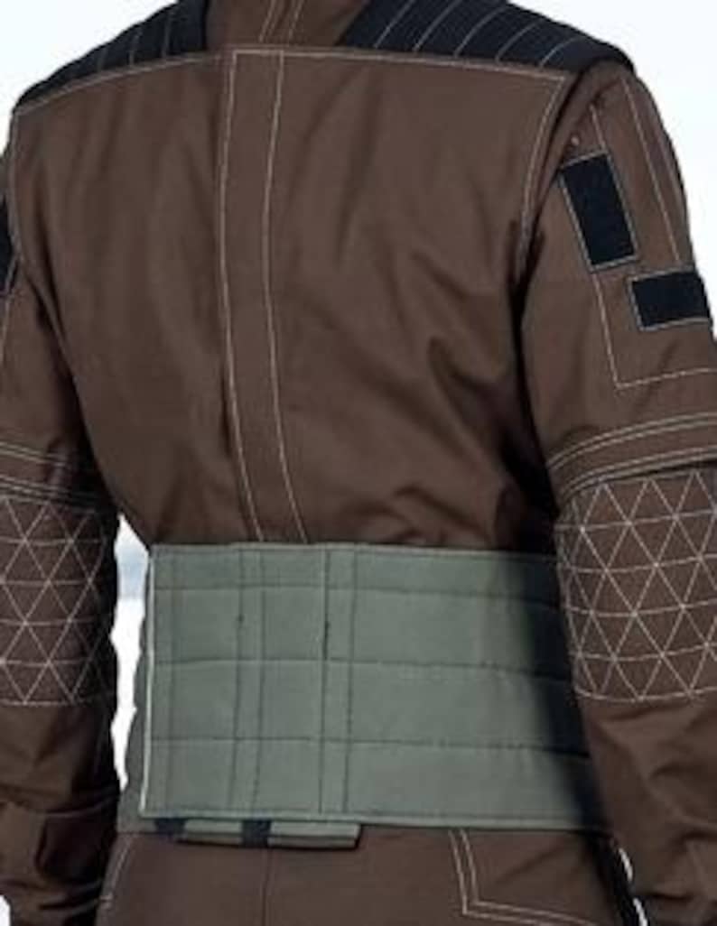 May include: A brown jumpsuit with geometric stitching on the shoulders and sleeves. The back view shows a light green quilted belt. Black velcro patches are visible on the upper arm.