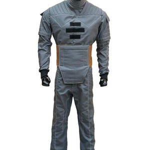 May include: Gray jumpsuit with a high collar, quilted shoulders, and a brown belt. The costume features black accents and stitching, with black gloves. The outfit is designed with a futuristic aesthetic.