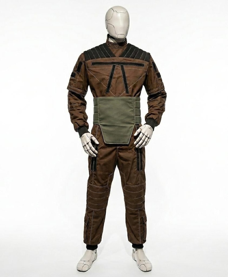 May include: A brown jumpsuit with black accents and a green waist belt is displayed on a mannequin. The outfit features black cuffs, white gloves, and white shoes. The mannequin has a white head.