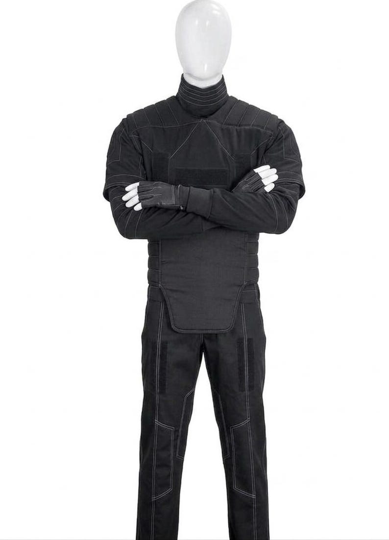 May include: Black tactical jumpsuit with a high collar, quilted detailing, and white stitching. The outfit includes matching gloves and pants. The mannequin is wearing the full outfit.