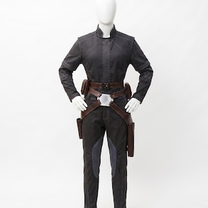 May include: A dark grey jumpsuit with a high collar, long sleeves, and visible stitching. The outfit includes a brown leather belt with pouches and a holster design. The trousers have grey panels on the front.