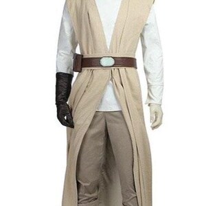 May include: A beige Jedi costume featuring a long, open-front robe, a white tunic, and matching pants. The costume includes a brown belt with a light blue buckle, a black glove, and matching boots. The outfit is displayed on a mannequin.
