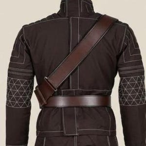 May include: A dark brown jacket featuring a high collar, long sleeves with white geometric stitching patterns, and a brown leather-like belt worn around the waist with a matching diagonal shoulder strap crossing over the back of the garment.