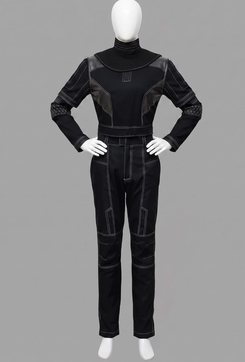 Peut inclure: Combinaison noire avec des d&eacute;tails de couture blancs, pr&eacute;sent&eacute;e sur un mannequin. La tenue pr&eacute;sente un col montant, des manches longues et une silhouette ajust&eacute;e. Le design comprend des panneaux g&eacute;om&eacute;triques et des coutures d&eacute;coratives.