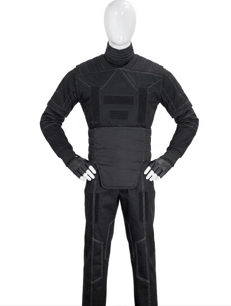 May include: A black tactical suit displayed on a mannequin. The suit includes a high-collared jacket with reinforced panels, matching pants, and gloves. White stitching accents the seams and panels. The overall design suggests a focus on protection and functionality.