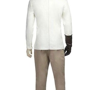 May include: A mannequin wearing a white long-sleeved jacket with a zipper down the back, paired with tan pants. The mannequin has a black glove on its right hand. The outfit is displayed against a white background.